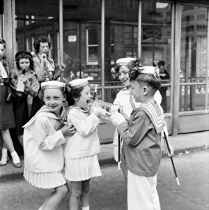 Two young friends taking part n the Manchester Whit Walks give a couple of girls a drink