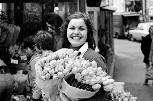 00068 Prints: A young girl of Amsterdam holding bunches of tulips during the season May 1975