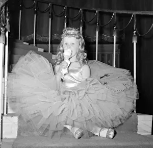Gown Prints: A young girl in her crinoline style ball gown takes an ice cream break during the Junior