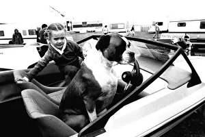 Motor Industry Prints: A young girl and her dog try out a speedboat at the Whitley Bay Motor Show. 18 / 07 / 80