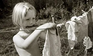 Housework Prints: A young girl hanging out the washing to dry at Hampstead day Nursery in London