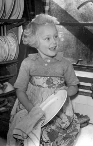 Chores Prints: Young girl helping out a home by doing the washing up Circa 1945 P044422