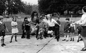 Young girl jumping over a skipping rope in the playground of the National School