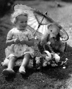 Toys Prints: Young girl sitting in her back garden shading her teddy bear from the sun underneatha