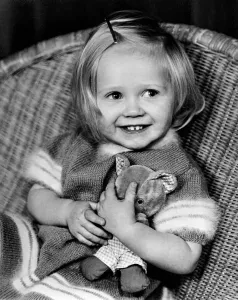 Toddler Prints: Young girl sitting in a wicker chair holding a teddy bear December 1969