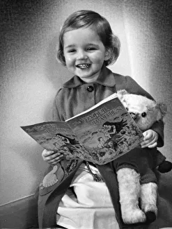 Teddy Bears Prints: Young girl smiling as she reads her Water Baies book Circa 1945 P044490