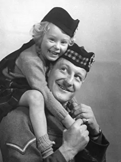 00041 Prints: Young girl wearing a hat with tartan design sitting of her fathers shoulder
