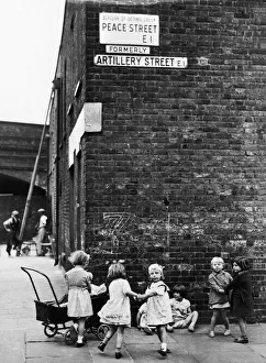 Pram Prints: Young girls playing mums with their dolls and toy prams on the corner of Peace Street