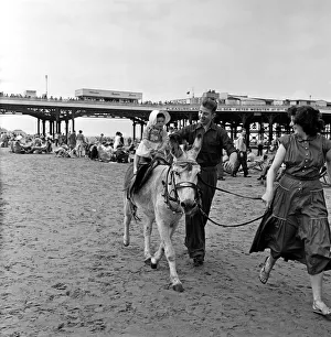 Donkey Prints: A young holiday makers having a Donkey ride on the beach at Blackpool, Lancashire