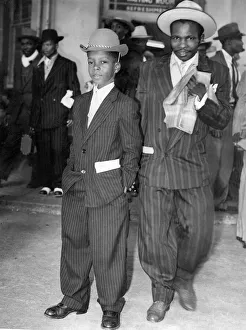 This young Jamaican boy in a striped suit and soft bowler hat has come to start a new