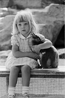 Toddler Prints: Young Kirsten Ogilvie with a baby penguin at the Cotswold WildLife Park in Oxfordshire