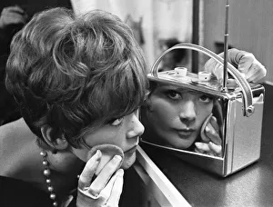 A young lady uses a chrome encased radio at the 1961 National Radio Show to touch up her