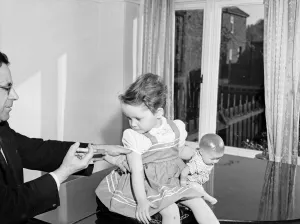 01149 Prints: A young patient looks on with trepidation whilst having her polio vaccination