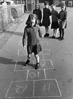 Young Pgirl playing a game oh hopscotch with her friends in the school playground