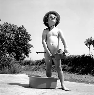 Young Prudence Ford age three years old playing outside in the garden with a watering