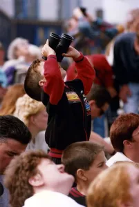 Air Display Prints: A young spectator looks through a pair of binoculars at an air display at the Sunderland