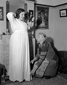 Overweight Prints: A young woman is giving a helping hand by her mother as she tries on a dress Circa
