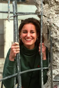 Young woman looks through a hole in the Berlin wall-pictured on the Jean Rook trip to