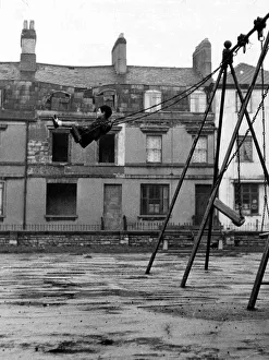 Alone Prints: A youngster enjoys the swing in a playground in the docks of Butetown in Cardiff