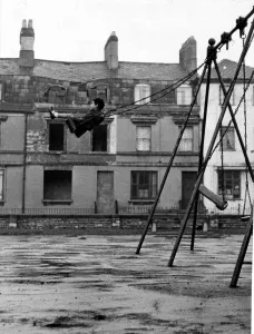 Alone Prints: A youngster enjoys the swing in a playground in the docks of Butetown in Cardiff